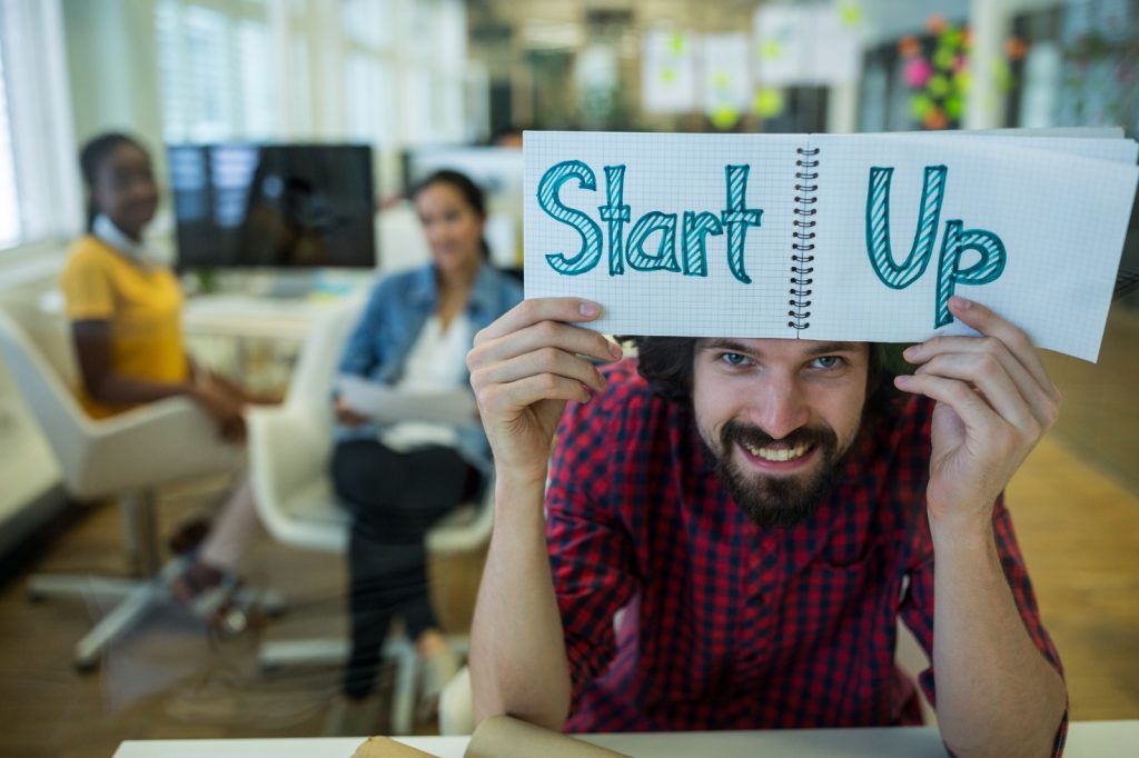 Group of professionals discussing startups, with one person holding a 'Startups' sign