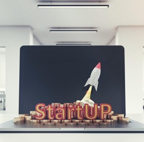 Startup rocket launching from coins and a laptop, symbolizing future business potential.