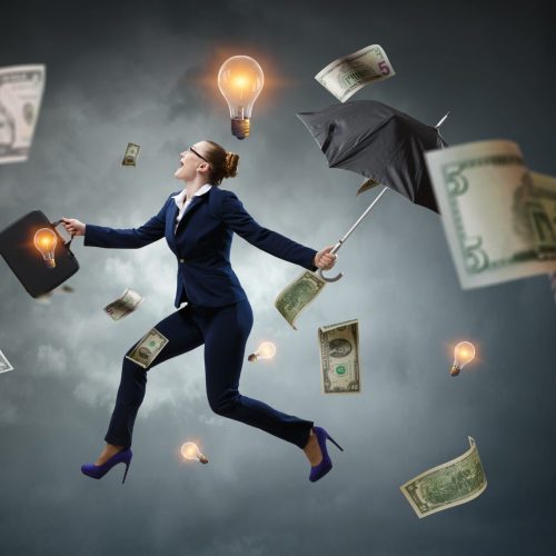 Entrepreneur in a suit walking under a storm of money and light bulbs, representing ideas.